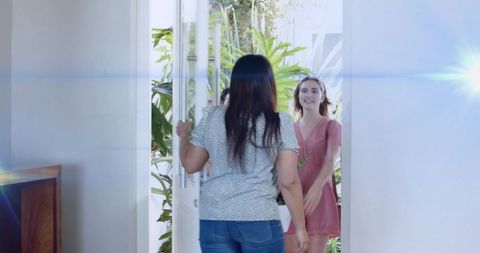 Welcoming guest at home entrance with sunlit doorway, leafy foyer, casual summer dress
