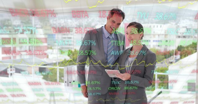 Business professionals analyzing stock market data displayed on a transparent digital screen. Ideal for use in articles or websites related to finance, investment strategies, economic trends, and business teamwork scenarios. Represents the use of technology and data analysis in corporate settings.