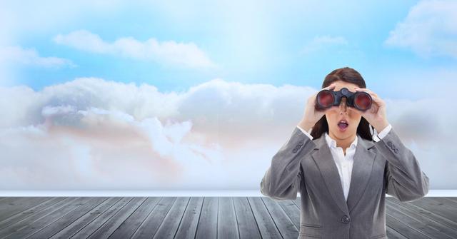 A businesswoman in a formal suit looks surprised while using binoculars against a bright, cloudy sky. She stands on wooden floorboards, suggesting an open space with a broad horizon. This image is ideal for illustrating concepts of vision, searching for opportunities, career focus, discovery, and facing the unknown in corporate and motivational contexts.