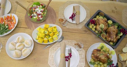 Rustic family feast celebrating communal roasted chicken dinner with corn, salad, rolls