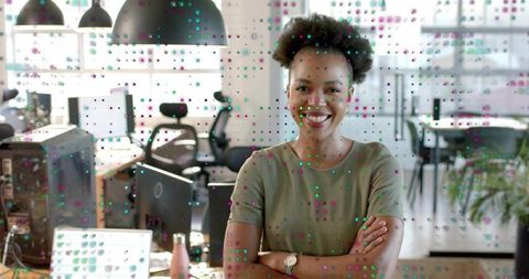 Smiling professional woman crossing arms in modern open office with glass partition