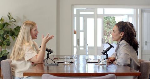 Two women recording podcast in stylish meeting room
