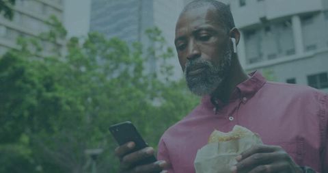 Man Enjoying Break with Smartphone and Sandwich in Urban Park