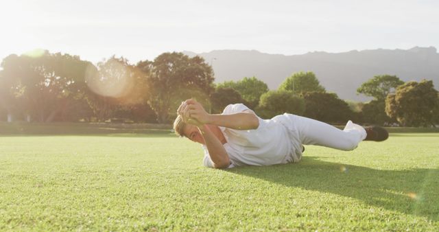 Cricketer diving to catch ball on grassy field on sunny day - Download Free Stock Images Pikwizard.com