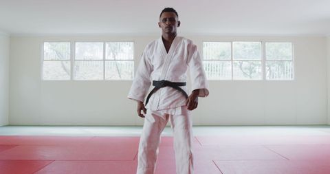Confident judo athlete standing in dojo wearing white gi