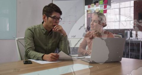 Coworkers Discussing Strategy with Documents and Laptop in Modern Office