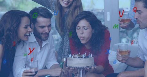 Friends celebrating birthday in living room woman blowing out candles on cake