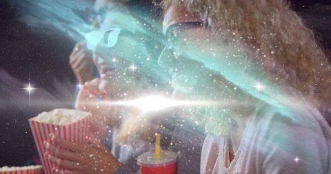 Women watching 3d movie surrounded by cosmic light in cinema