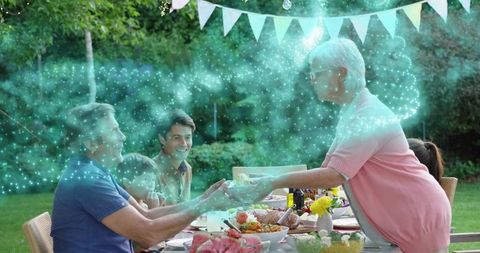 Grandmother passing dish at multigenerational backyard dinner with turquoise sparkle