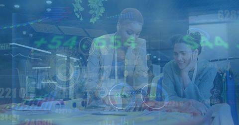 Fashion designers collaborating in creative studio with digital interface