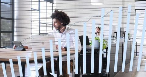 Man working on laptop and tablet with growth chart overlay in modern coworking office