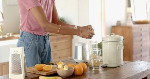 Woman Preparing Fresh Citrus Juice in Bright Kitchen Environment