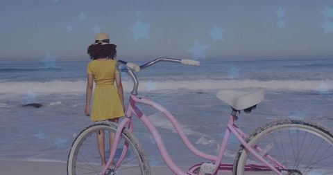Woman in Yellow Dress with Bike at Sunlit Beach