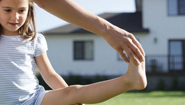 Parent lifting child stretching leg in backyard playful bonding and balance