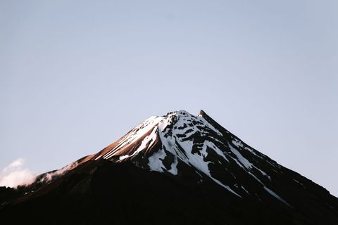 Sunlight Highlighting Snow-Capped Volcanic Peak Against Clear Pastel Sky, Minimal Landscape