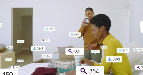 Couple sorting clothes during move with digital notification icons and coffee cups
