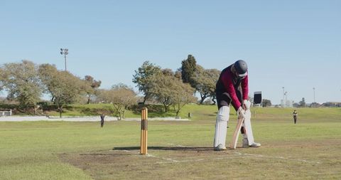 Cricket Player Prepares Equipment on Field Under Clear Sky