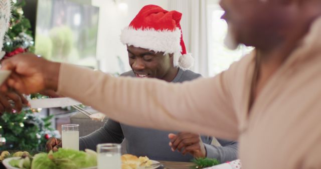 Family members gathering for a festive Christmas meal, enjoying time together. Santa hat conveys holiday spirit. Ideal for holiday festive concepts, family gatherings, festive meal celebrations, and Christmas traditions.