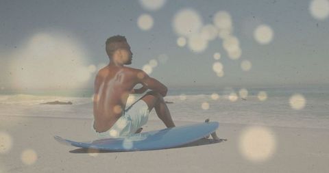 Man Relaxing on Beach with Surfboard Under Sunlit Sky