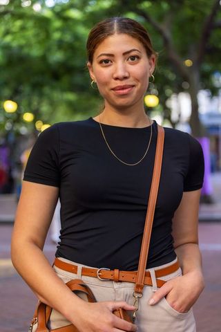 Confident african american woman on tree-lined plaza at dusk with leather crossbody bag