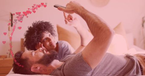 Happy couple relaxing at home using smartphone with heart animation
