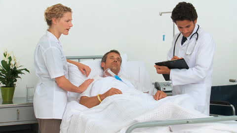 Doctors Conducting Hospital Visit with Patient in Bed