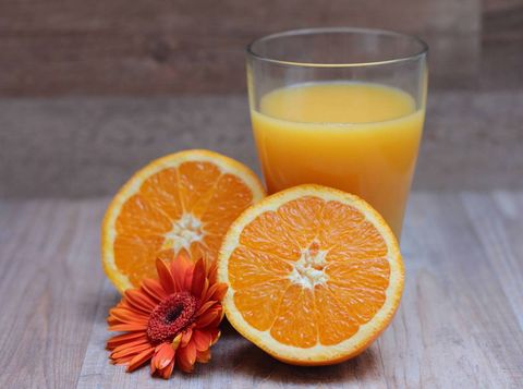 Refreshing orange juice with fresh halved oranges and gerbera