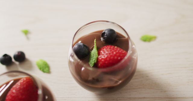 Image of chocolate pudding with strawberries and bluberries on a wooden surface - Download Free Stock Photos Pikwizard.com