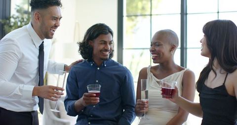 African american friends laughing and toasting with wine at casual daytime gathering