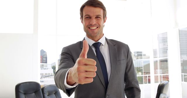Happy businessman giving thumbs up in his office
