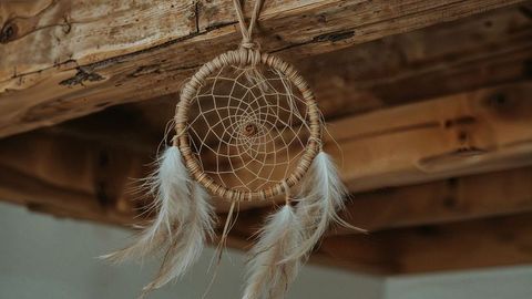 Dreamcatcher adorns rustic wooden beam in cozy interior