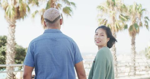 Happy Couple Strolling along Sunny Seaside Promenade