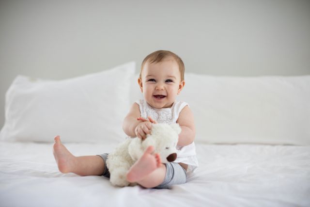 Cute baby girl playing with soft toy on bed - Download Free Stock Photos Pikwizard.com
