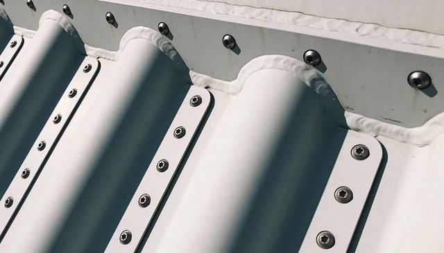 Corrugated metal roof close-up with rounded ribs, weld bead and exposed fasteners