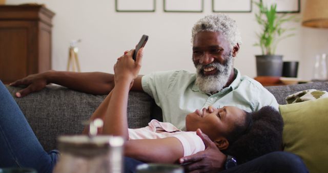 Happy Father and Daughter Relaxing on Couch and Using Smartphone - Download Free Stock Images Pikwizard.com