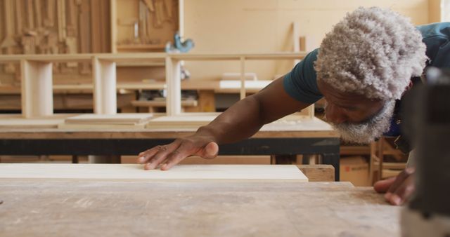 African american male carpenter blowing the dust over wooden plank at a carpentry shop - Download Free Stock Photos Pikwizard.com