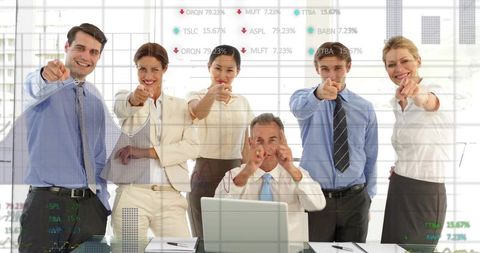 Executives pointing at camera in bright modern office with laptop analytics and teamwork