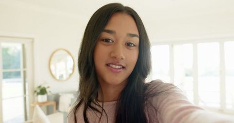 South Asian Woman Smiling Selfie in Minimalist Room