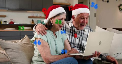 Senior couple wearing santa hats using laptop and celebrating holiday video call