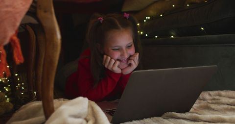 Girl Using Laptop under Holiday-Themed Blanket Fort