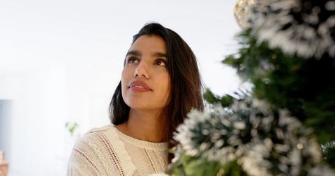 Woman reflecting by decorated christmas tree in cozy living room