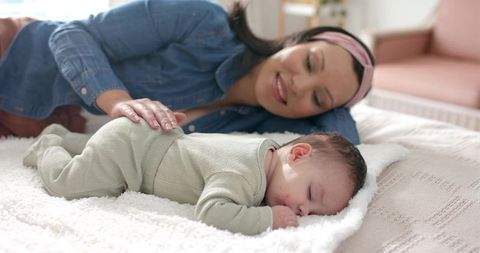 Mother Comforting Baby on Cozy Blanket by Sunny Window