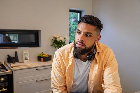 Man relaxing in contemporary kitchen with headphones and fruit bowl