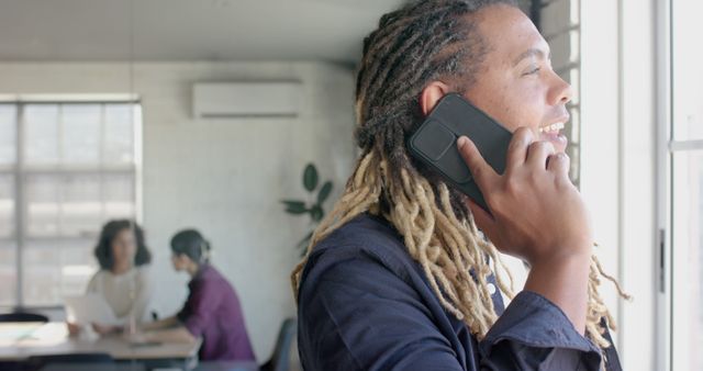 Smiling Man with Dreadlocks Talking on Phone in Office - Download Free Stock Images Pikwizard.com