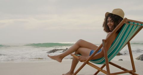 Smiling Woman Relaxing in Lounger on Coastal Beach