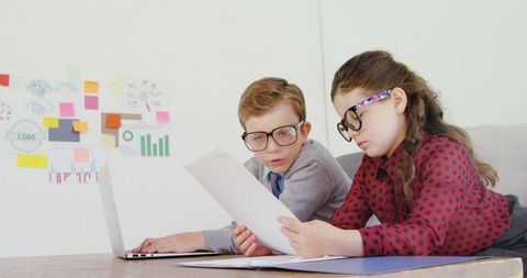 Children in business attire analyzing document in office