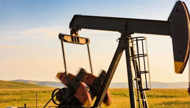 Pumpjack horsehead lifting on grassland oilfield golden hour sunset industrial landscape