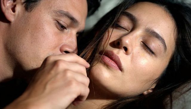 Intimate couple caressing face and hair while lying together closeup romantic moment