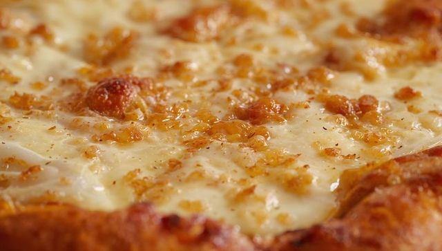Melting mozzarella pizza bubbling and browning with golden garlic crumbs and glazed crust
