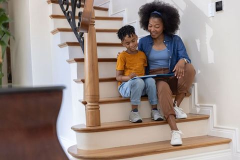 African american mother and son reading together on wooden staircase sharing warm family moment